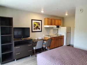 埃佩克斯WoodSpring Suites Raleigh Apex的小房间设有一张床和一间带电视的厨房