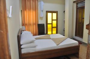 Stone TownPlumeria Motel - Stone Town Zanzibar的一间卧室配有带白色床单和枕头的床。