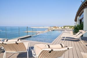 切齐纳码头Palace Lido Hotel & Suites的一个带椅子的甲板和一个海景游泳池