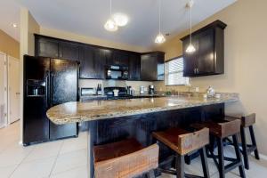 南帕诸岛Kingfisher的厨房配有黑色橱柜和带凳子的台面