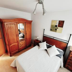 克尤伯厄拉斯APARTAMENTO EN SEGUNDA LINEA DE MAR, WIFI & A.C的一间卧室配有一张大床和一个木制橱柜