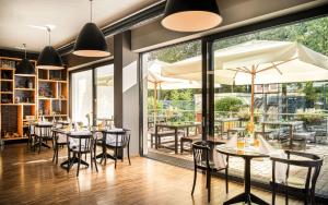 美因河畔法兰克福法兰克福曼豪斯斯坦德酒店的餐厅设有桌椅和大窗户。