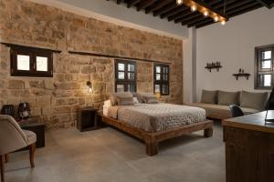 罗德镇Ancient Knights Luxury Suites的一间卧室设有一张床和石墙