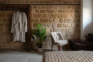 罗德镇Ancient Knights Luxury Suites的一间卧室配有一张床、一把椅子和砖墙