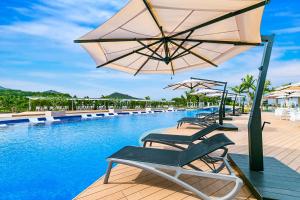 名户Oriental Hotel Okinawa Resort & Spa的一个带椅子和遮阳伞的游泳池