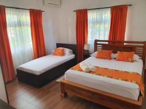 安塞奥潘格雷斯自助式公寓的配有橙色窗帘和窗户的客房内的两张床