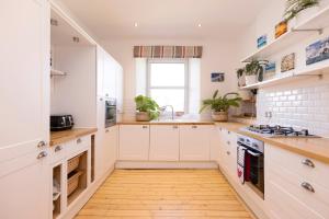 爱丁堡JOIVY Gorgeous 1-bed flat with a shared garden的厨房铺有木地板,配有白色橱柜。