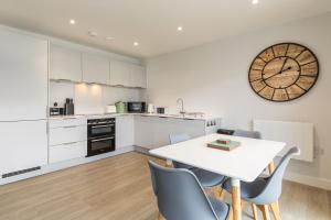 伍拉科姆4 Challacombe - Luxury Apartment at Byron Woolacombe, only 4 minute walk to Woolacombe Beach!的厨房配有桌椅和墙上的时钟