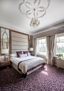 科巴姆伍德兰公园酒店的一间卧室配有一张大床和一个吊灯。