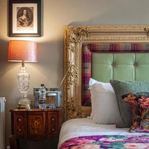 戈德尔明The Kings Arms and Royal Hotel, Godalming, Surrey的一张带金框的床和一张桌子上的灯