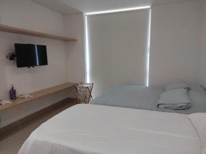 GairaEdificio Reserva del Mar, Paya Salguero , Santa marta的卧室配有白色的床和平面电视。