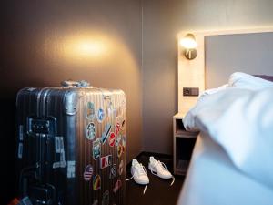 柏林阿勒托库单酒店的酒店客房带行李箱和一双鞋