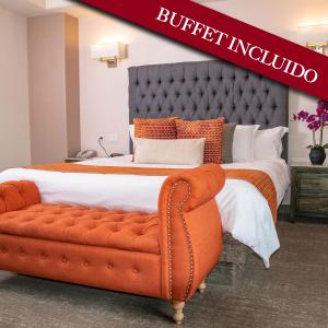 提华纳迪奇安酒店的一张大床,在房间内配有橙色沙发