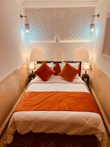 马拉喀什Riad Ajmal的一间卧室配有一张带橙色枕头的大床