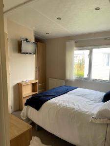 查珀尔圣伦纳兹bracken lodge的卧室配有一张床,墙上配有电视。