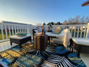 塞顿港Prestige caravan,Seton Sands holiday village, WiFi的甲板配有桌椅和地毯