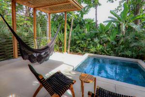 圣塔特蕾莎海滩Hotel Nantipa - A Tico Beach Experience的游泳池旁的吊床和椅子