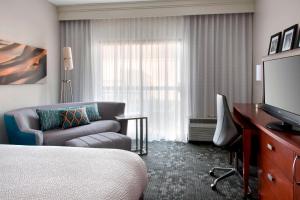 米德尔敦纽波特米德尔顿万怡酒店的酒店客房配有床、沙发和电视。