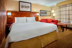 丹弗斯波士顿丹弗斯万怡酒店的酒店客房设有一张大床和一张红色沙发。