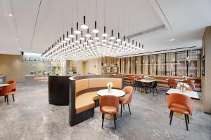 胶州青岛胶东国际机场亚朵酒店的一间带桌椅和吊灯的餐厅