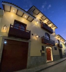 库斯科Hotel Hacienda Cusco Centro Historico的一座大型白色建筑,设有两个阳台和车库