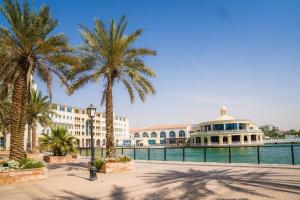 迪拜Copthorne Lakeview Executive Apartments Dubai, Green Community的一群棕榈树和水边的一座建筑