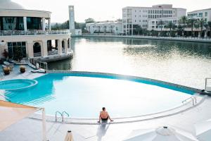 迪拜Copthorne Lakeview Hotel Dubai, Green Community的一个人坐在游泳池里
