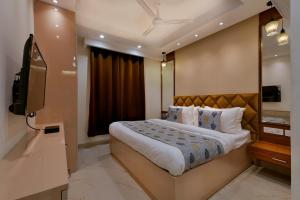 新德里Hotel Leo Saffron - Corporate Stay Pitampura的一间卧室配有一张大床和电视