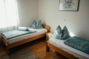 HartmannsdorfGästehaus Jeindl的客房设有两张带蓝色枕头的床。