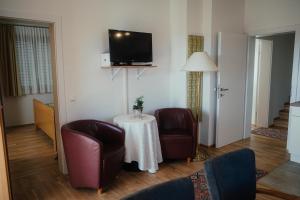 HartmannsdorfGästehaus Jeindl的客厅配有两把椅子、一张桌子和一台电视
