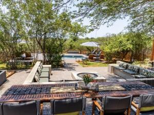 侯斯普瑞特Muunga Bush Lodge & Spa的一个带桌椅的庭院和一个游泳池