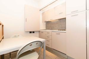 都灵Open Space 53 con Parcheggio in Struttura e Colazione deliziosa的厨房配有白色橱柜和桌椅