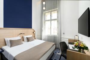 布达佩斯Hotel Oktogon Haggenmacher by Continental Group的一间卧室配有一张床、一台电视和一把椅子
