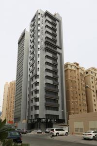 科威特Saray Prime Suites的停车场内停放汽车的大型建筑