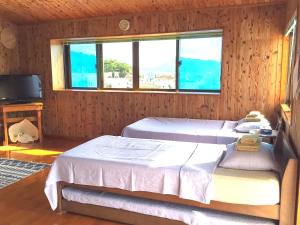 座间味村亚朵卡丽旅馆的一间卧室设有两张床和窗户。