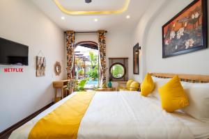 会安An Nhien Boutique Villa的一间卧室配有一张带黄色枕头的大床