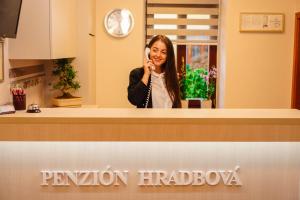 科希策Penzión Hradbová Residence & Spa的一名妇女在柜台后面用手机说话