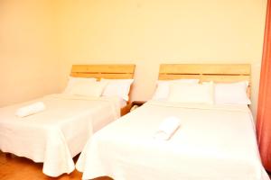 吉塞尼Musanto Hotel的两张睡床彼此相邻,位于一个房间里