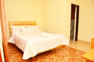 吉塞尼Musanto Hotel的一间卧室配有带白色床单和枕头的床。
