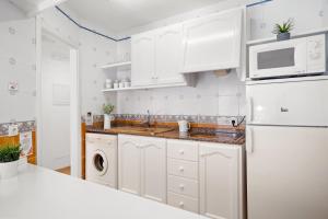 蓬塔普里马Punta Prima Apartments的厨房配有白色橱柜和白色冰箱。