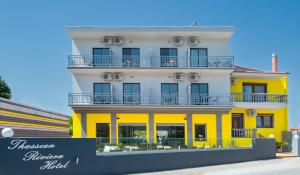 普利瑙港湾Thassian Riviera Hotel的黄色和白色的建筑,前面有标志