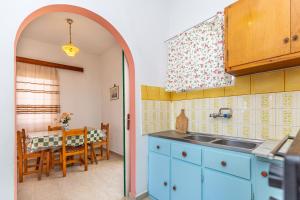 贝尼蔡斯Alexandros Studios by Estia的一间设有蓝色橱柜的厨房和一间带桌子的用餐室