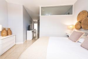 阿德耶Apartamentos Barranco del Infierno的一间白色卧室,配有一张大床和一个厨房