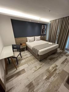 马卡埃Golden Towers Hotel的一间卧室配有一张床、一张桌子和一把椅子