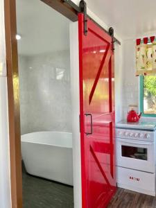 Kampong NailSea Kecil Tiny House near Jetty of Kuala Besut的一间带浴缸和炉灶的浴室内的红色门