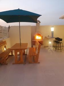 Hal GhaxiakB&S Accommodation Penthouse 602的庭院设有桌子、遮阳伞和壁炉。