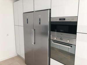 卡贝塞拉什德巴什图Casa do Barroso的一间厨房内的不锈钢冰箱,厨房内有白色的橱柜