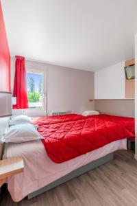 勒鲁Premiere Classe Rennes Ouest - Le Rheu的卧室里一张红色的大床,卧室里设有窗户