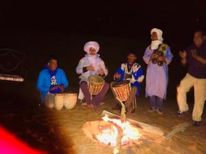 梅尔祖卡Riad Hotel Les Flamants的一群人围坐在火炉旁