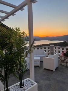 卡波利韦里SUNSET SUITE的一个带白色家具和棕榈树的庭院,享有日落美景